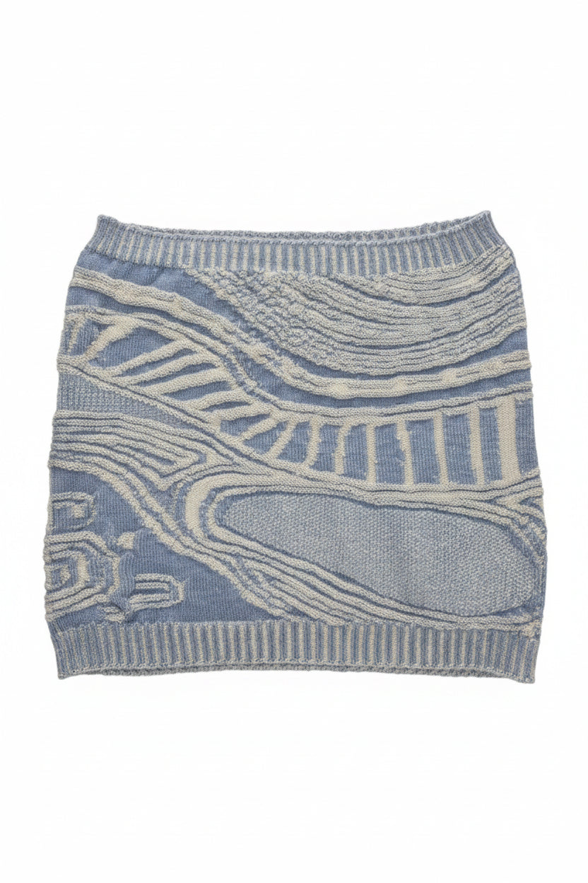 A light blue and off-white patterned knit sweater or cardigan laid flat on a beige carpet background.